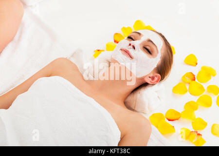 Thérapeute l'application d'un masque de visage à la face d'une belle jeune femme blonde à l'aide d'un pinceau cosmétique Banque D'Images