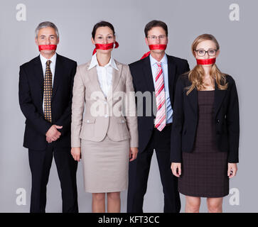 Businesspeople lié par une bande rouge autour de leur bouche standing in a row incapable de parler ou de divulguer de l'information Banque D'Images