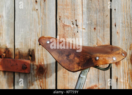 Selle en cuir d'un vélo. Ancienne selle sur fond de mur en bois. Banque D'Images