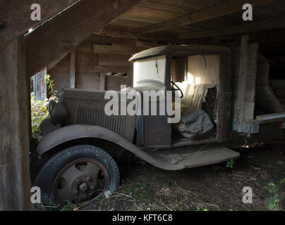 Un camion vintage se trouve abandonné dans une ancienne grange (années 1800) sur une ferme dans la campagne Moretown, Vermont, États-Unis Banque D'Images