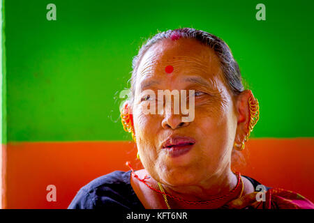 Pokhara, Népal - novembre 04, 2017 : portrait de vieille femme qui pose pour appareil photo de Pokhara, Népal, dans un arrière-plan vert et orange Banque D'Images