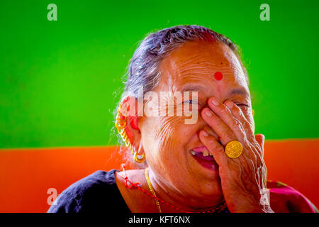 Pokhara, Népal - novembre 04, 2017 : portrait de vieille femme qui pose pour appareil photo de Pokhara, Népal, dans un arrière-plan vert et orange Banque D'Images