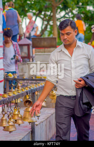 Pokhara, Népal, 10 octobre 2017 non identifié : businessman touching les cloches de tailles différentes en barahi taal mandir, Pokhara, Népal Banque D'Images