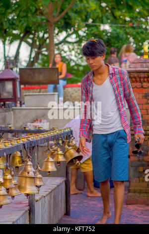 Pokhara, Népal, 10 octobre 2017 : Jeune homme touchant les cloches de tailles différentes en barahi taal mandir, Pokhara, Népal Banque D'Images