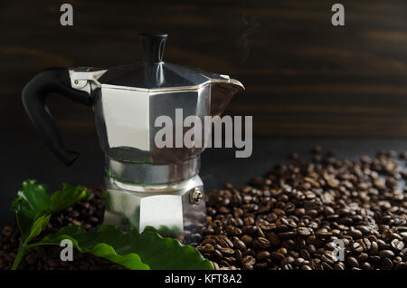 Tasse de café et les grains de café avec des feuilles sur fond noir Banque D'Images