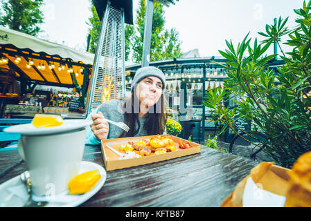 Belle femme manger en café à l'extérieur Banque D'Images