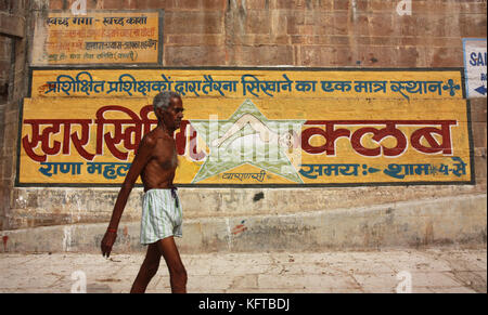 L'homme marche le long des Ghats en direction de Varanasi Swimming Club sur les rives de la rivière sacrée Ganges, Varanasi, Inde Banque D'Images