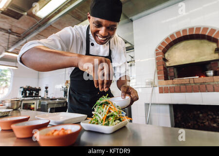 Male chef preparing salad en cuisine. Gourmet chef rendre plat délicieux dans une cuisine de restaurant. Banque D'Images