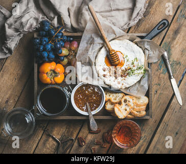 Camambert avec du miel, des noix, des herbes, fruits et vin rose Banque D'Images