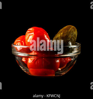 Concombre salé avec des tomates en vase en verre. un bol de tomates rouges et de concombre, isolé sur un fond noir Banque D'Images