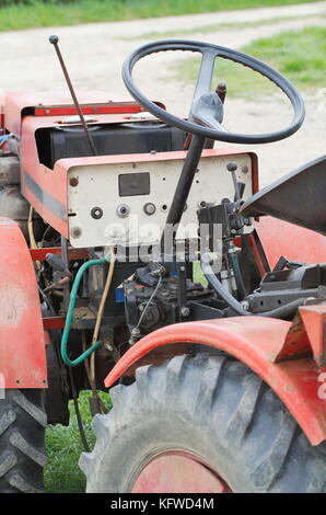 Sale petit tracteur rouge vieux gros plan sur le chemin de terre Banque D'Images