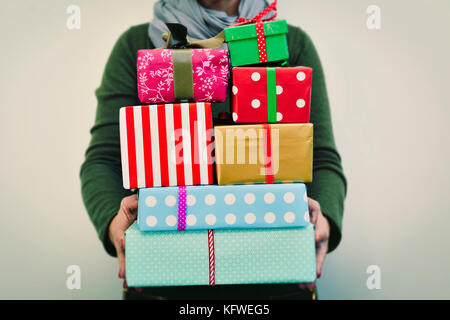 Libre d'un young caucasian woman holding une pile de cadeaux dans ses mains enveloppées dans des documents de nice et attachées avec des rubans de couleurs différentes Banque D'Images