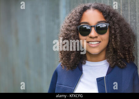 Beautiful happy mixed race african american girl adolescent femme jeune femme portant des lunettes de soleil à l'extérieur avec des dents blanches parfaites smiling Banque D'Images