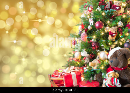 Noël arrière-plan flou artistique avec l'or, les lumières de l'arbre de Noël décoré, boîte cadeau rouge et l'ours en peluche. Banque D'Images