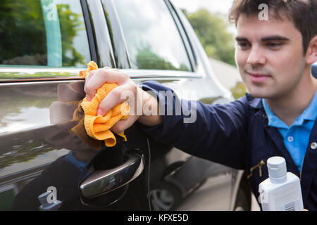 Le polissage de l'homme porte de la voiture au cours de service voiturier Banque D'Images