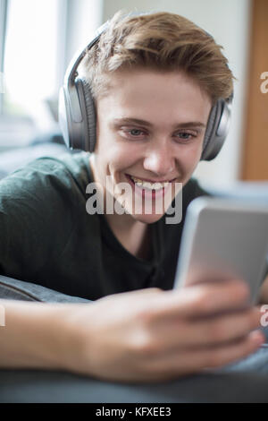 Teenage boy streaming de musique à partir d'un téléphone portable sur un casque sans fil Banque D'Images