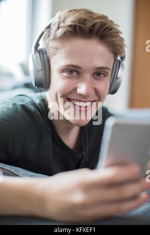 Teenage boy streaming de musique à partir d'un téléphone portable sur un casque sans fil Banque D'Images