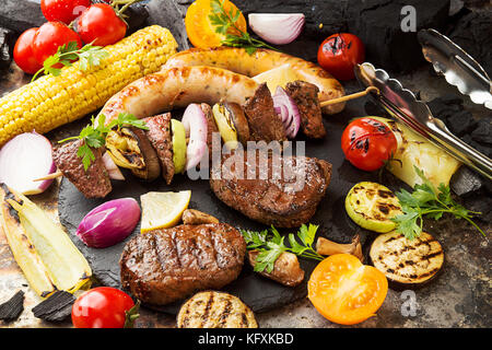 Un assortiment de délicieux barbecue grillé avec légumes viande. Beef steaks grillés avec des brochettes de boeuf, saucisses, maïs, tomate cerise, poivre, tranches de Banque D'Images