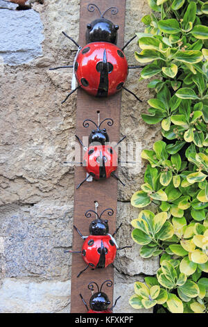 Ornements de jardin en forme de coccinelles , affiché sur le mur de pierre, Espagne Banque D'Images