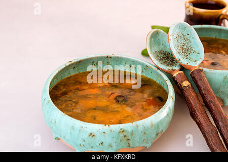 Soupe avec de la viande, viande fumée, saucisses, concombres, tomates, olives, herbes, citron dans un bol bleu sur fond de béton gris, des plats faits maison. Trad Banque D'Images