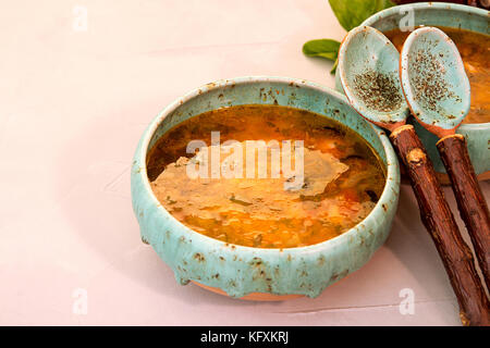 Soupe avec de la viande, viande fumée, saucisses, concombres, tomates, olives, herbes, citron dans un bol bleu sur fond de béton gris, des plats faits maison. Trad Banque D'Images