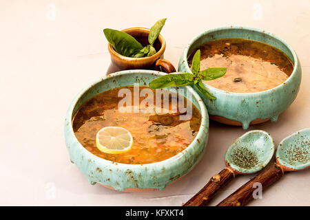 Soupe avec de la viande, viande fumée, saucisses, concombres, tomates, olives, herbes, citron dans un bol bleu sur fond de béton gris, des plats faits maison. Trad Banque D'Images