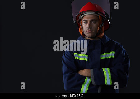 Portrait of smiling fireman standing avec ses mains croisées Banque D'Images