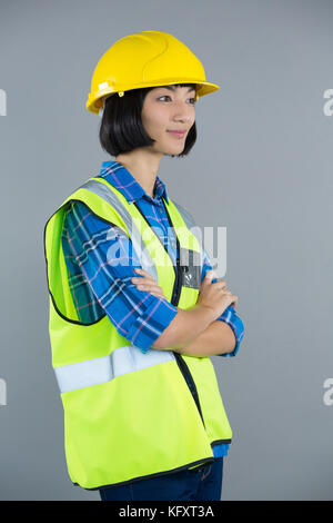 Female architect standing with arms crossed contre l'arrière-plan gris Banque D'Images