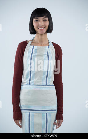 Portrait of smiling waitress in apron standing against white background Banque D'Images