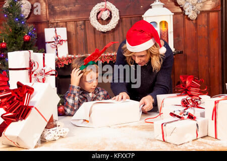 Charmant petit garçon prépare les cadeaux de Noël avec sa mère Banque D'Images