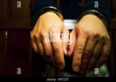 Abstract. Les mains du prisonnier sur un treillis en acier de près. L'homme en prison, menottes. Détail des mains avec de l'acier des menottes. Banque D'Images