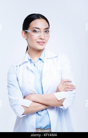 Cheerful lab worker dans des verres de sécurité posant contre fond blanc Banque D'Images