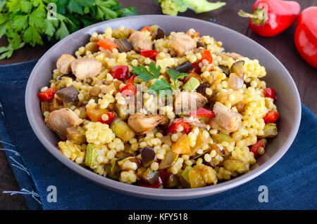 Un régime alimentaire léger avec salade, couscous de légumes (courgettes, aubergines, carottes, poivrons, oignons), les morceaux de poulet sur un fond de bois foncé Banque D'Images
