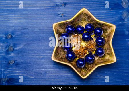 Le bleu et or de Noël Décoration dans une cuvette en forme d'étoiles dorées sur un fond de bois bleu Banque D'Images