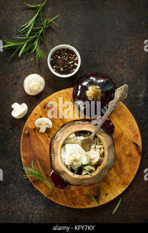 Quenelles au four dans un pot avec champignons et sauce à la crème aigre sur une pierre ou l'ardoise. Banque D'Images