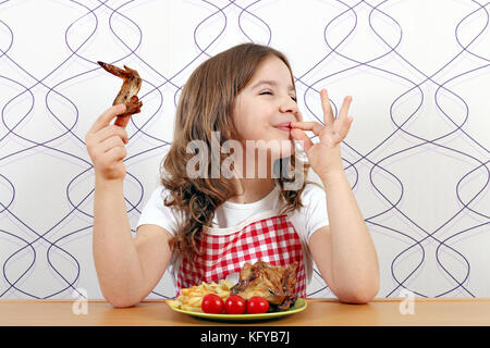 Happy little girl avec des ailes de poulet et la main ok sign Banque D'Images
