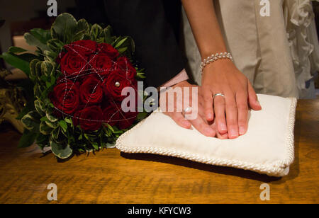 Les anneaux de mariage de la part d'un couple de mariés et un bouquet de roses rouges Banque D'Images