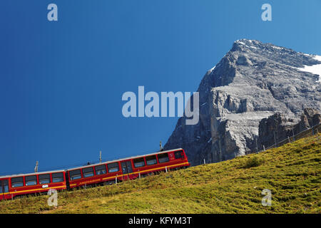 Les wagons rouges de la Jungfrau se trouvent sous la face nord de l'Eiger à Kleine Scheidegg, dans l'Oberland bernois, en Suisse Banque D'Images