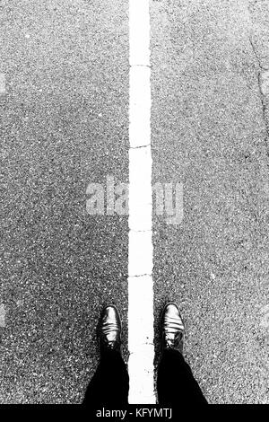 Chaussures femme debout au-dessus de la ligne blanche qui sépare gauche et droite. Debout sur le côté à la fois. Notion de bien et mal, bon et mauvais, et Banque D'Images