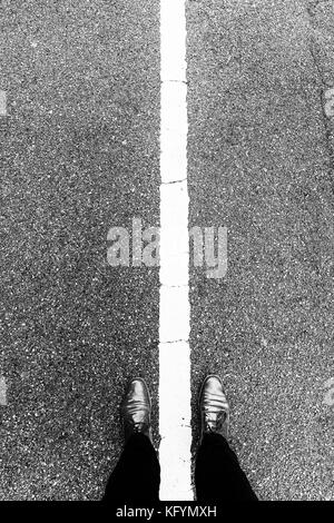 Chaussures femme debout au-dessus de la ligne blanche qui sépare gauche et droite. Debout sur le côté à la fois. Notion de bien et mal, bon et mauvais, et Banque D'Images