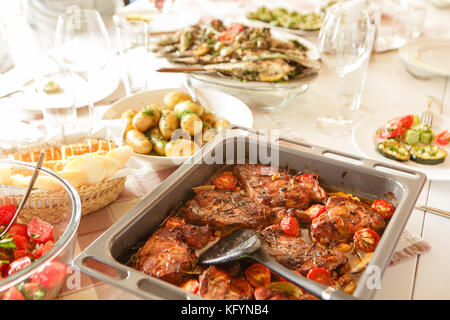 La viande cuite au four avec tomates et pommes de terre sur une plaque de cuisson, table de service Banque D'Images