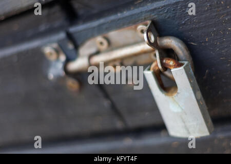 Un cadenas rouillé verrouillé sur un boulon coulissant en position LOCK (verrouillage sur une boîte de bois Banque D'Images