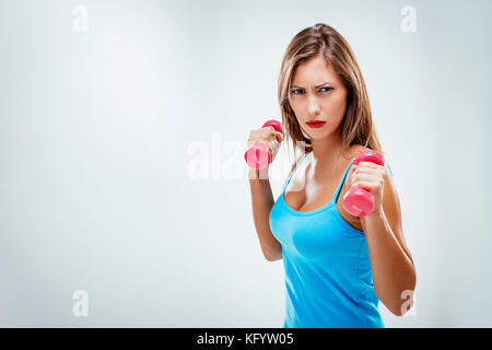 Belle femme de remise en forme avec sérieux, faire de l'exercice de levage d'armes formation haltères. isolé sur fond blanc. Banque D'Images