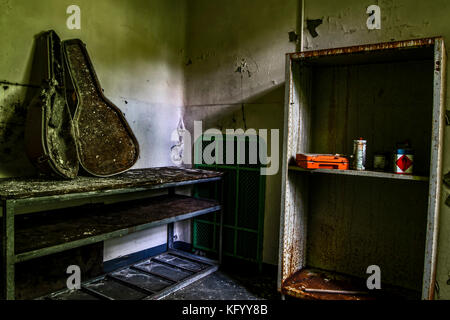 Un étui à guitare sur une table entièrement brûlé, dans une chambre d'un hôpital psychiatrique abandonné Banque D'Images