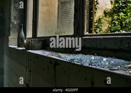 Quelques morceaux de verre sur un mur dans une chambre d'un hôpital psychiatrique abandonné Banque D'Images