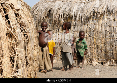 Komote, KENYA - 12 juillet : groupe d'enfants de la tribu elmolo jouant autour de maisons rondes traditionnelles de l'herbe dans le village komote au Kenya, ko Banque D'Images