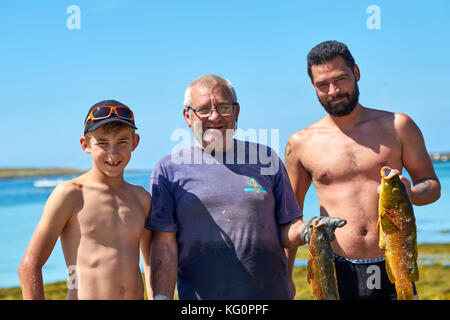 Trois générations de pêcheurs locaux avec leurs prises sur les îles Glenan situées au large de la côte ouest du Finistère près de Concarneau Bretagne France. Banque D'Images