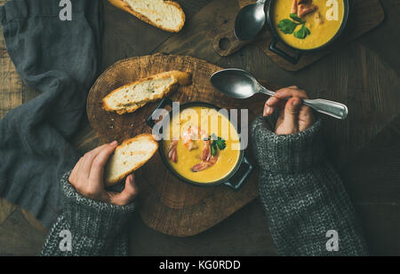 Femme chandail gris chaud en mangeant de la soupe de maïs aux crevettes chaudrée crémeuse servi dans des pots individuels, vue d'en haut. La femme' s part maintenant du pain et cuillère chrit Banque D'Images