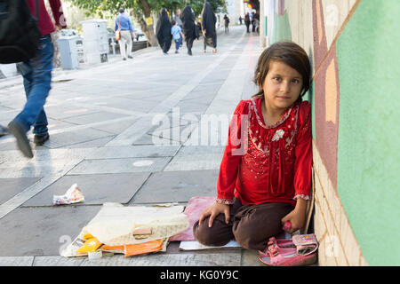 Téhéran, Iran - le 16 août 2017 une petite marchande de petits paquets de tissus au niveau de la rue pavé devant mur peint Banque D'Images