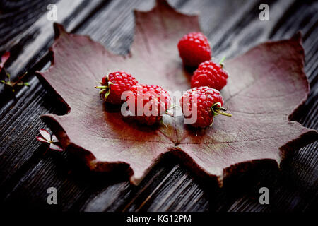 Grand beau framboise se trouve sur une plaque d'argile sous la forme d'une feuille d'érable. Banque D'Images